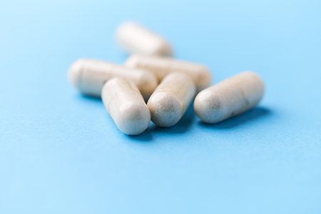 Close up of white capsules on blue background. Focus on foreground.の写真素材