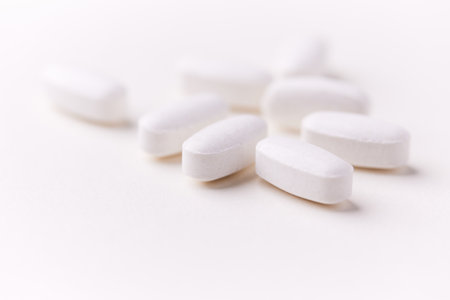 White pills on a white background. Focus on foreground, soft bokeh.