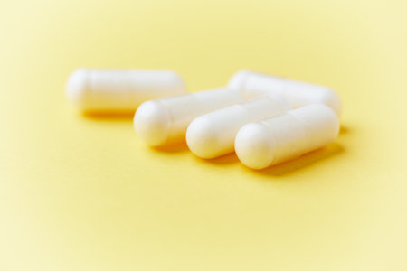 White pills on yellow background. Focus on foreground, soft bokeh.