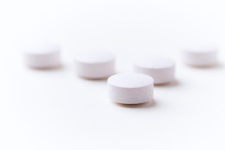 Close-up of white pills on white background. Focus on foreground, soft bokeh.