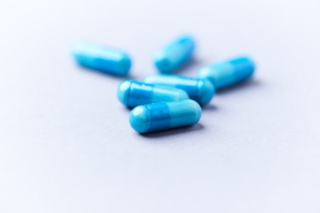 Blue pills on a white background. Focus on foreground, shallow DOF.
