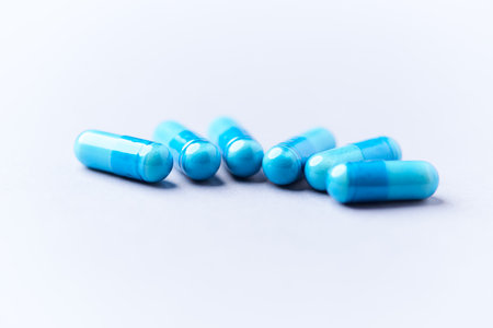 Blue pills on white background. Focus on foreground, soft bokeh.