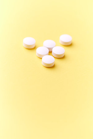 White pills on a yellow background. Focus on foreground, soft bokeh.