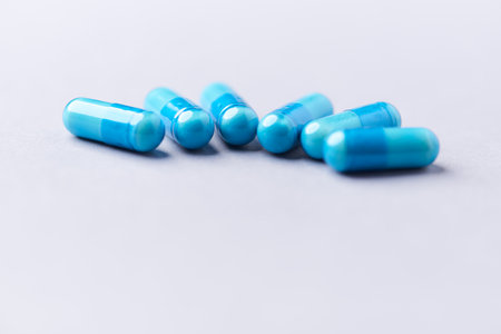 Blue pills on a white background. Focus on foreground, soft bokeh.