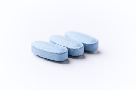 Blue pills on white background. Focus on foreground, soft bokeh.