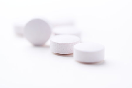 Close up of white pills on white background. Focus on foreground, soft bokeh.