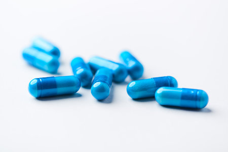 Blue pills on white background. Shallow depth of field. Focus on foreground.