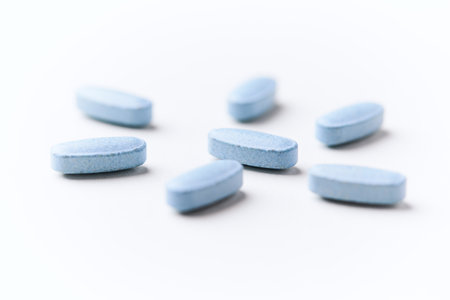 Blue pills on white background. Focus on foreground, soft bokeh.