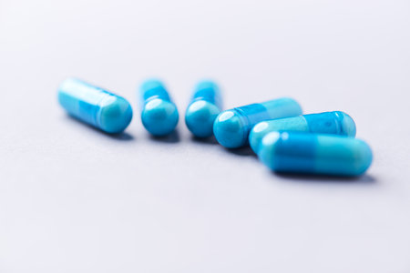 Blue pills on a white background. Focus on foreground, soft bokeh.