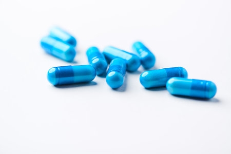 Blue pills on white background. Focus on foreground, soft bokeh.の写真素材