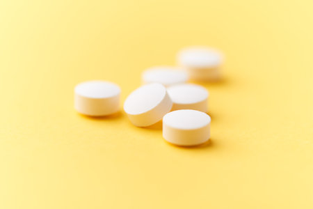 White pills on yellow background. Focus on foreground, soft bokeh.