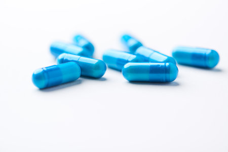 Blue medical capsules on white background. Focus on foreground, soft bokeh.の写真素材