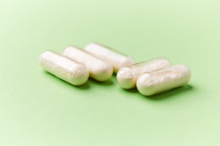 Close up of a group of white pills on a green background.