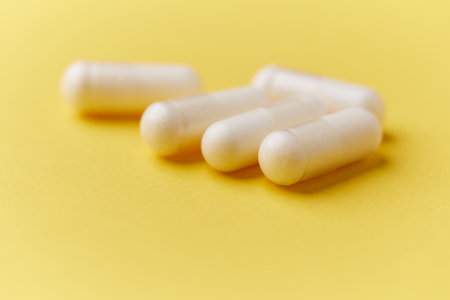 Close-up of white pills on yellow background. Focus on foreground.の写真素材