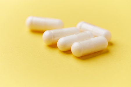 White pills on yellow background. Focus on foreground, soft bokeh.