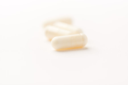 Close up of white pills isolated on white background. Focus on foreground, soft bokeh.