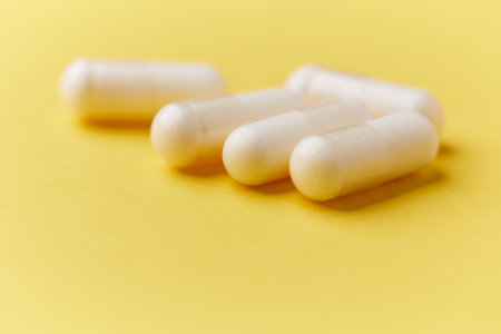 White pills on a yellow background. Focus on foreground, soft bokeh.