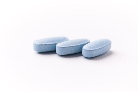 Blue pills on white background. Focus on foreground, soft bokeh.