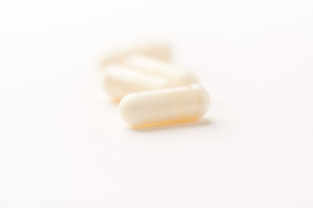Close up of white pills on white background. Focus on foreground.