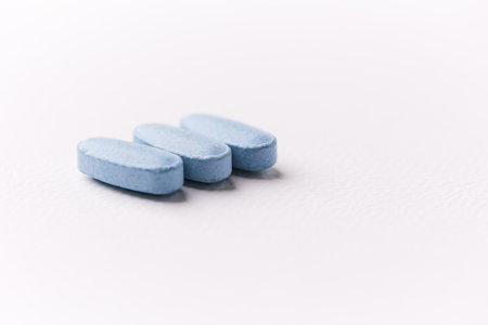Blue pills on white background. Focus on foreground, soft bokeh.の写真素材