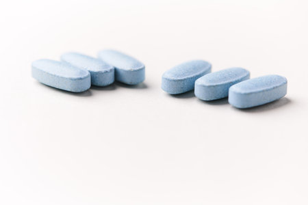 Blue pills on white background. Focus on foreground, soft bokeh.