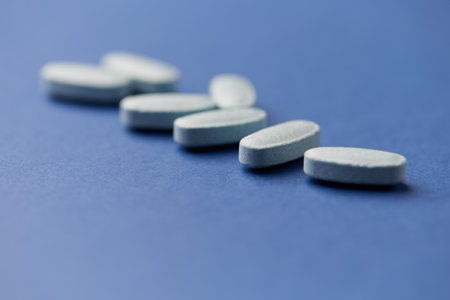 White pills on blue background. Focus on foreground, soft bokeh.