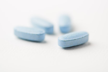 Blue pills on white background. Focus on foreground, soft bokeh.