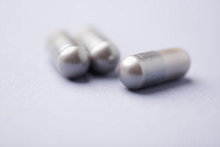 Close-up of two silver pills on white background. Focus on foreground.