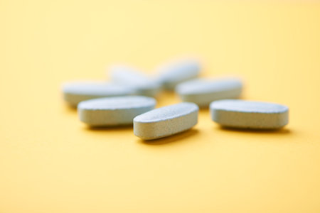 Close up of pills on yellow background. Focus on foreground, soft bokeh.