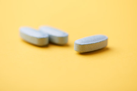 Pills on a yellow background. Focus on foreground, soft bokeh.