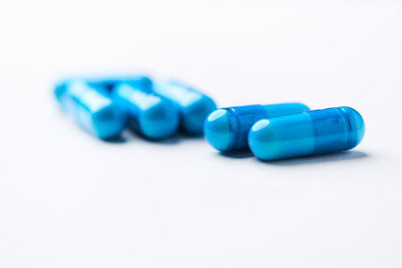 Blue pills on a white background. Focus on foreground, shallow depth of field.