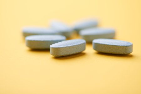 Pills on a yellow background. Focus on foreground, soft bokeh.