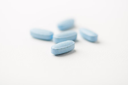 Blue pills on white background. Focus on foreground, soft bokeh.