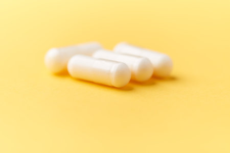 Close up of white pills on yellow background. Focus on foreground, soft bokeh. Pharmacy drugstore...
