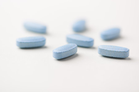 Blue pills on white background. Focus on foreground, soft bokeh.