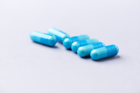 Blue pills on a white background. Focus on foreground, soft bokeh.