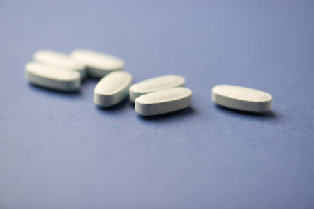 White pills on blue background. Focus on foreground, soft bokeh.
