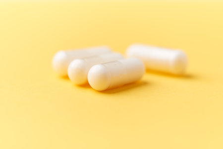 White pills on yellow background. Focus on foreground, soft bokeh.