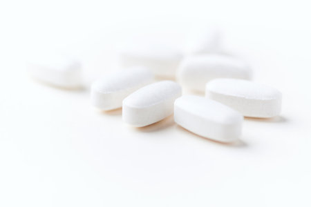 White pills on white background. Focus on foreground, soft bokeh.
