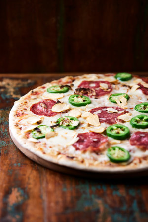 Pizza with salami and green peppers on a wooden background.の写真素材