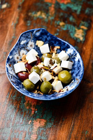 Greek salad with feta cheese, olives and nuts on wooden table