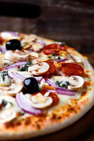 Pizza with mushrooms, olives and cheese on a wooden backgroundの写真素材