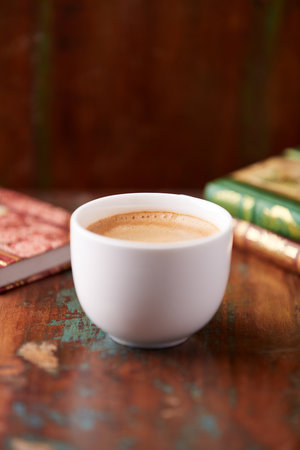 Coffee cup and books on old wooden table, selective focus