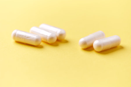Close up of white pills on yellow background. Focus on foreground.の写真素材