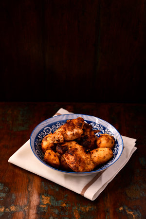 Fried chicken fillet with potatoes in a blue ceramic bowl on a wooden backgroundの写真素材