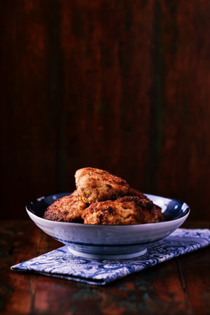 Fried meatballs in a bowl on a wooden background.