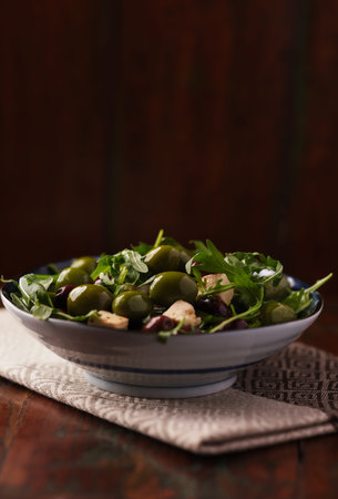 Green salad with olives, capers and arugula in a bowlの写真素材