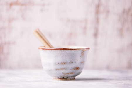 Empty ceramic bowl with wooden spoon on white wooden background. Selective focus.の写真素材