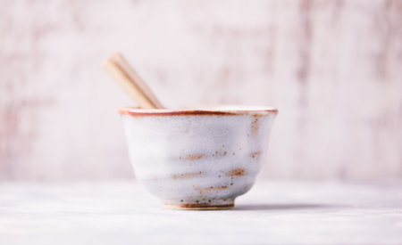 Ceramic bowl and wooden spoon on a white wooden background.の写真素材