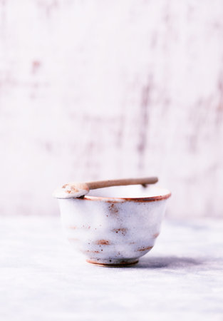 Vintage ceramic bowl with spoon on a light background. Selective focus.の写真素材